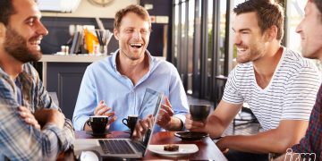 L'immagine rappresenta un gruppo di uomini giovani a un tavolo.