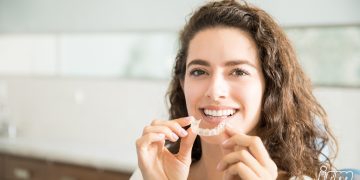 L'immagine rappresenta una ragazza con in mano un apparecchio dentale.
